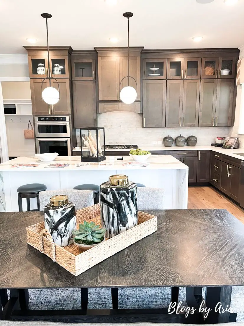 The Statesville model by Caruso Homes gourmet kitchen with dark wood stained cabinets and light quartz countertops