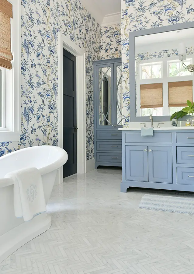 bathroom with blue print wallpaper and soft blue cabinets