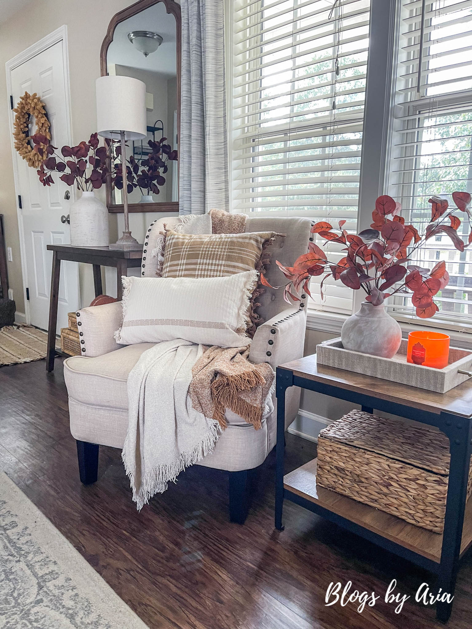 fall accent chair with brown plaid pillow and throw blanket, fall floral arrangement with fall candle